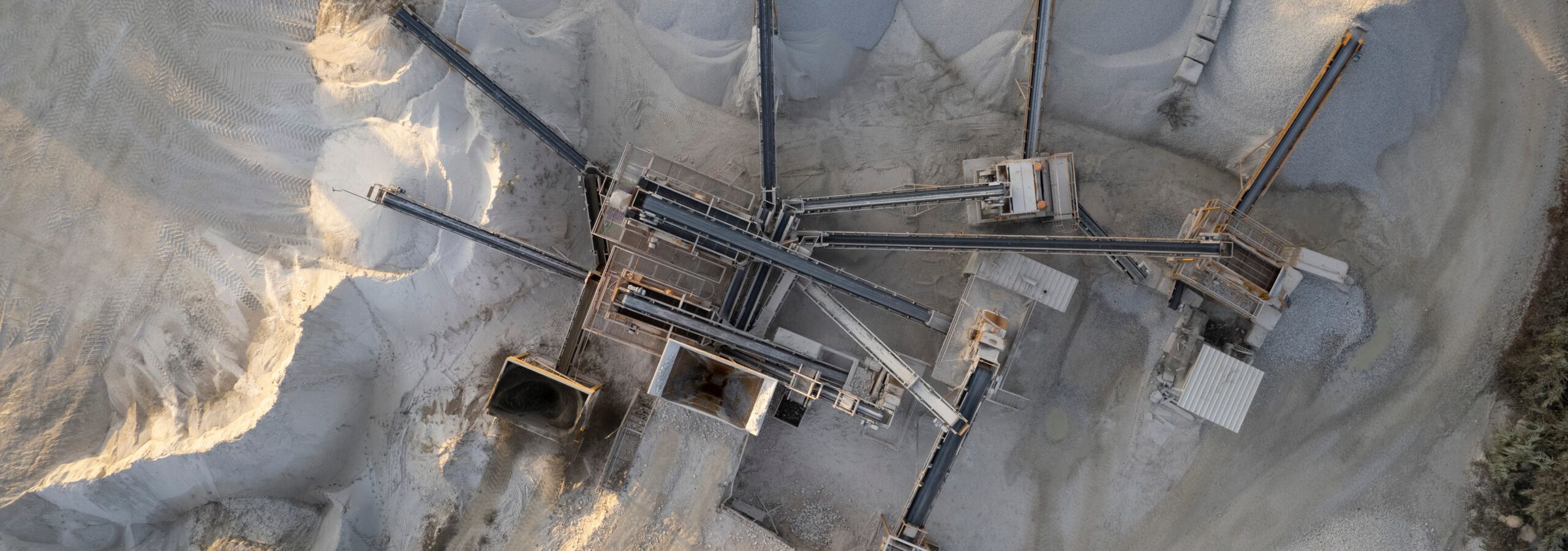 Tavolino rotondo bianco, vasca da bagno in ceramica e vaso per piante in un bagno moderno e lussuoso con luce solare e ombra di foglie su una parete di piastrelle di granito per l'esposizione di prodotti per la cura della persona e articoli da toilette